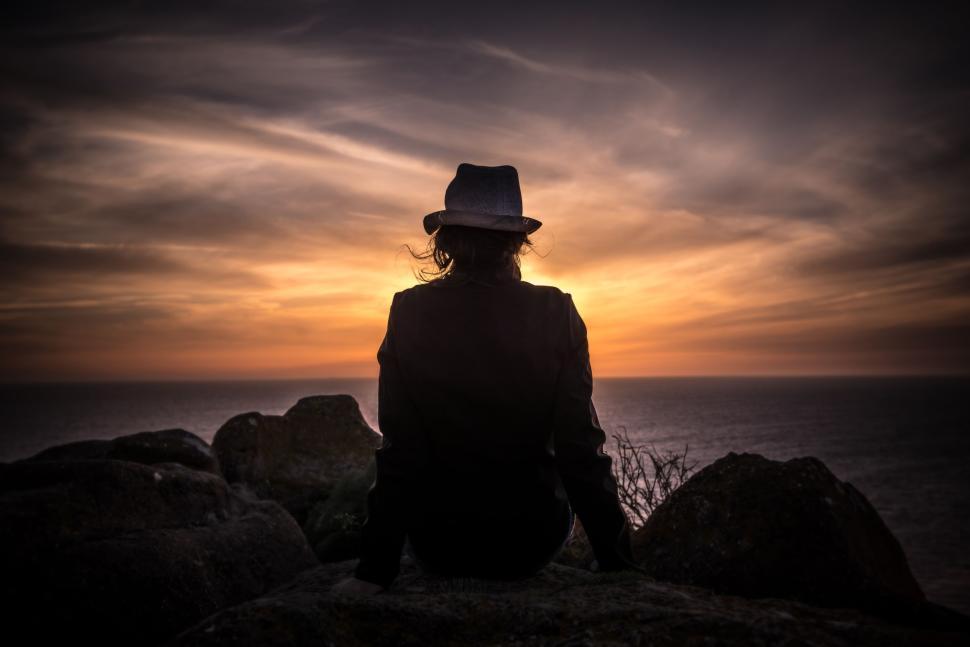 Free Image of Silhouette of person in hat watching sunset by sea. 