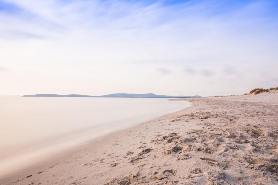 Free Image of Serene empty beach with gentle waves under blue skies 