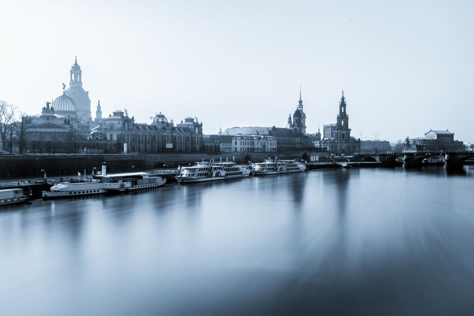 Free Image of Boats lined along a river embankment with city skyline 