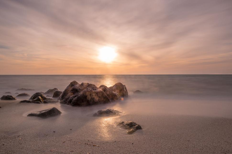 Free Image of Calm ocean sunset with rocks and smooth water surface 