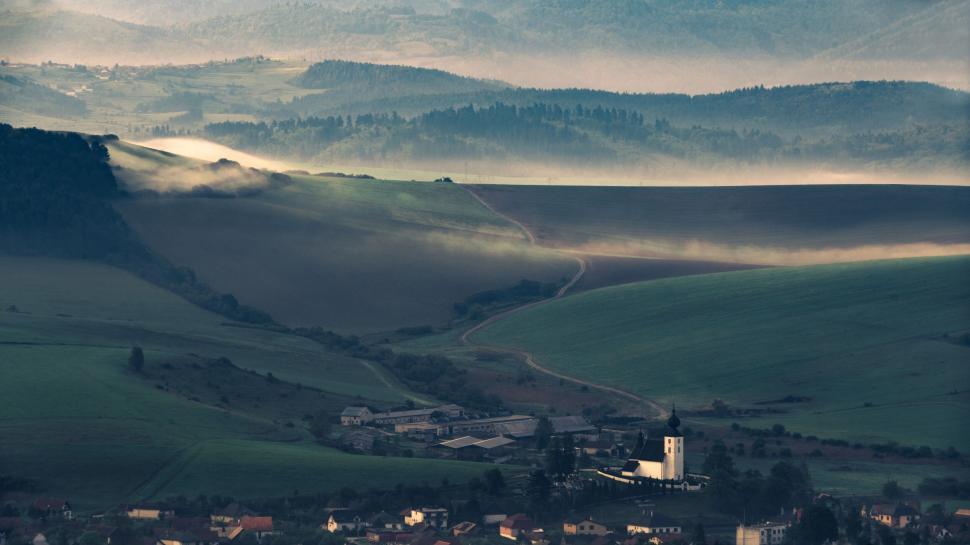 Free Image of Misty rural landscape with fields, hills, and a church 