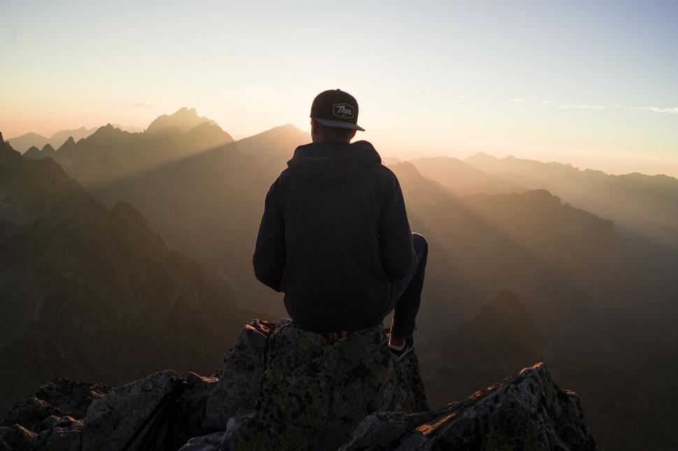 Free Image of Hiker at sunrise on mountain peak with light rays 