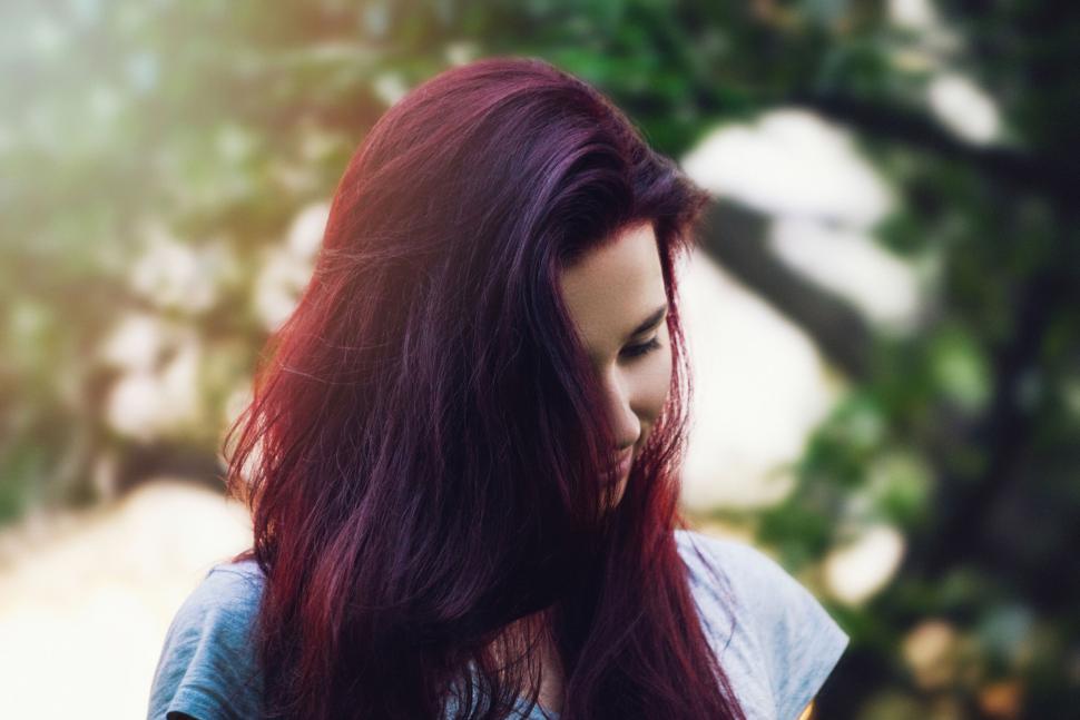 Free Image of Person with red hair standing outdoors on a nature walk. 