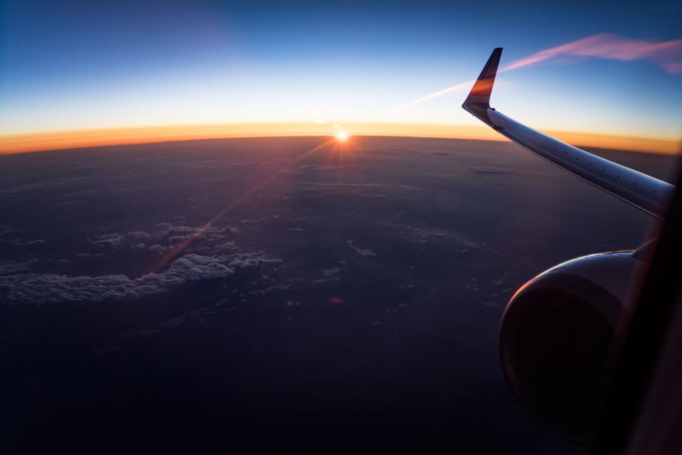 Free Image of Sunset view from airplane window, wing visible in frame 