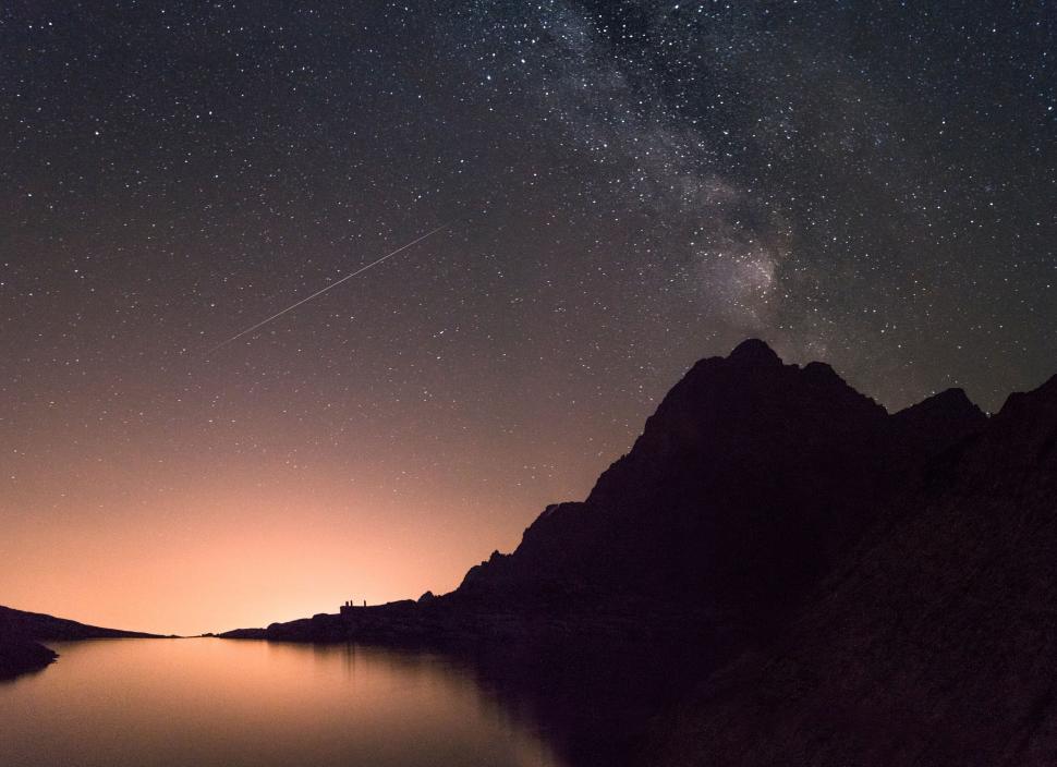 Free Image of Night sky with stars reflecting in a calm water body. 