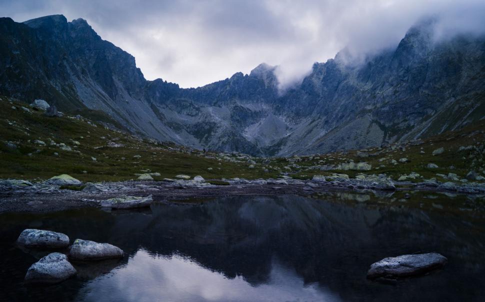 Free Image of Mountain range with misty peaks and a calm lake below. 