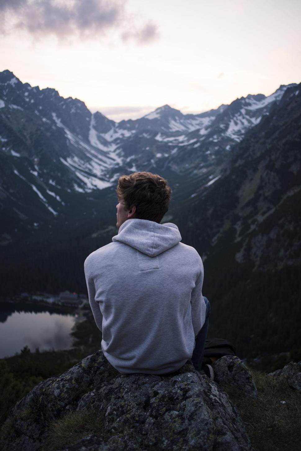 Free Image of Person sitting on mountain observing scenic valley. 