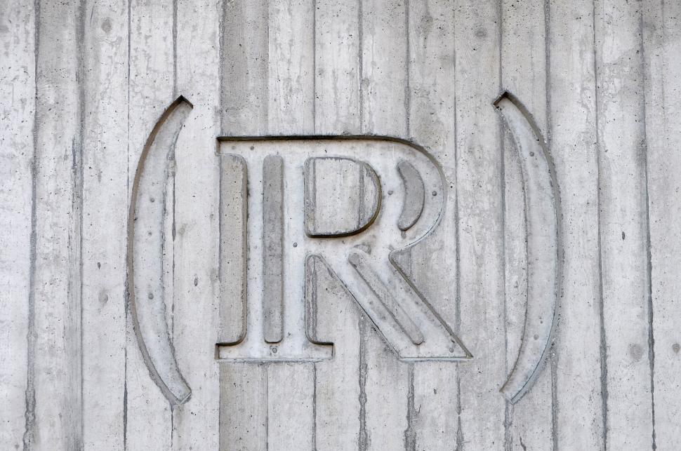Free Image of Concrete wall with carved  R  symbol and parentheses. 