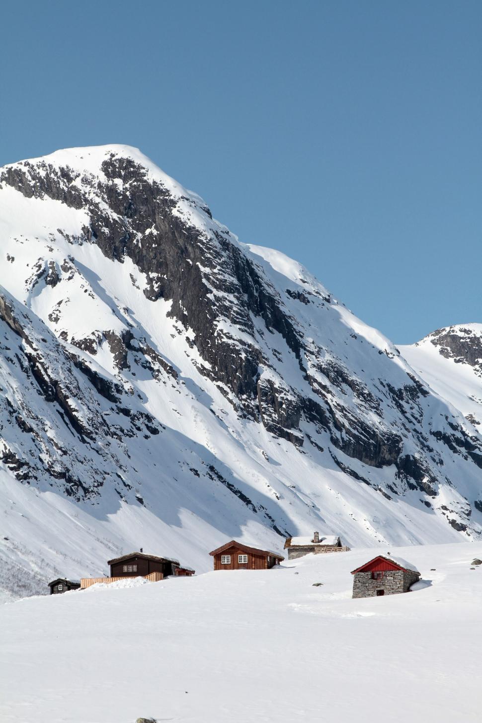 Free Image of Snowy mountain peak with cozy cabins in the foreground 