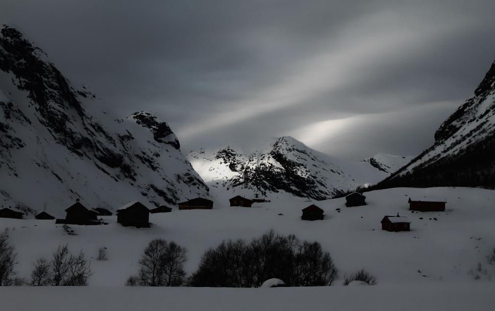 Free Image of Snow-covered village at dusk surrounded by towering peaks 