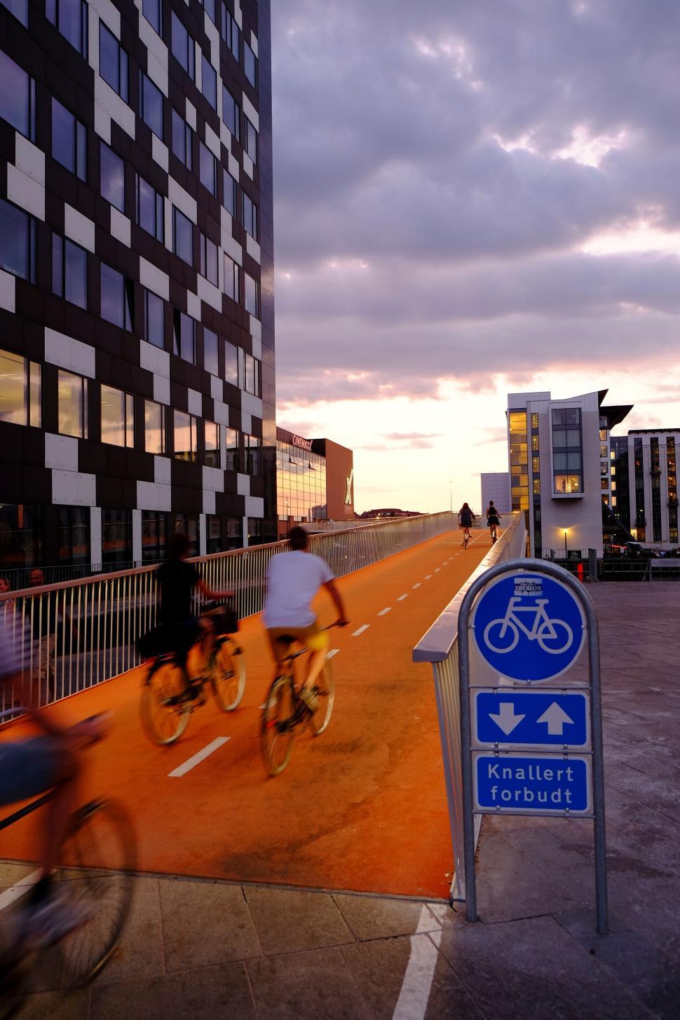 Free Image of Cyclists riding on modern orange bike path at sunset 