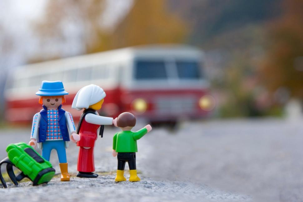 Free Image of Family figures waiting for a bus on a countryside road. 