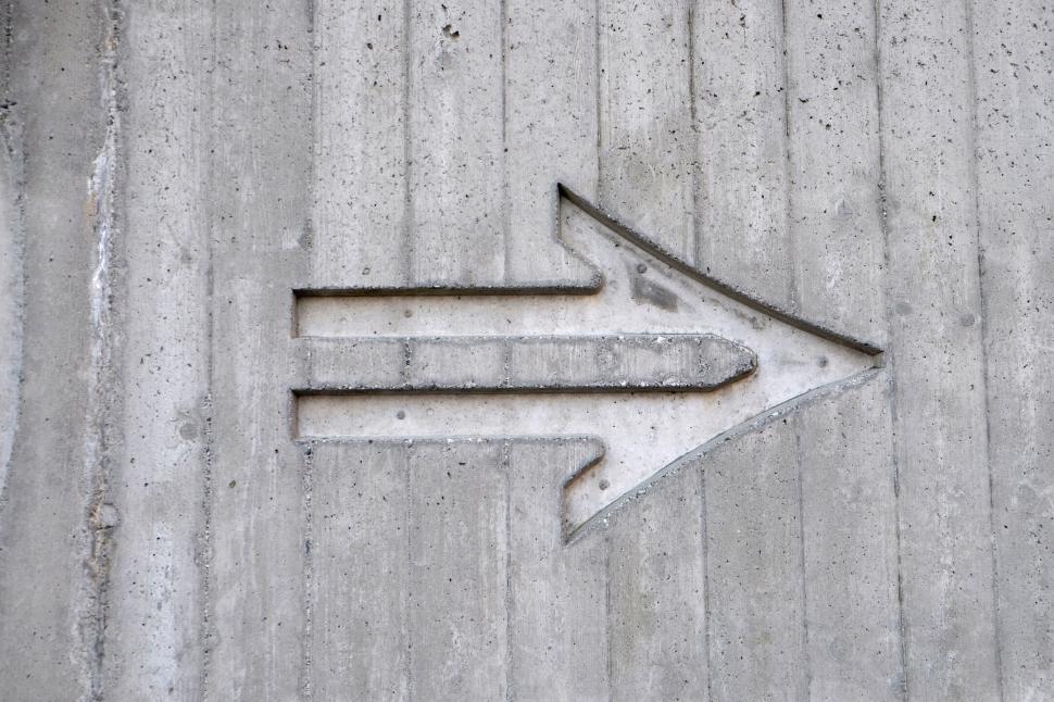 Free Image of Concrete wall with large engraved arrow pointing right. 