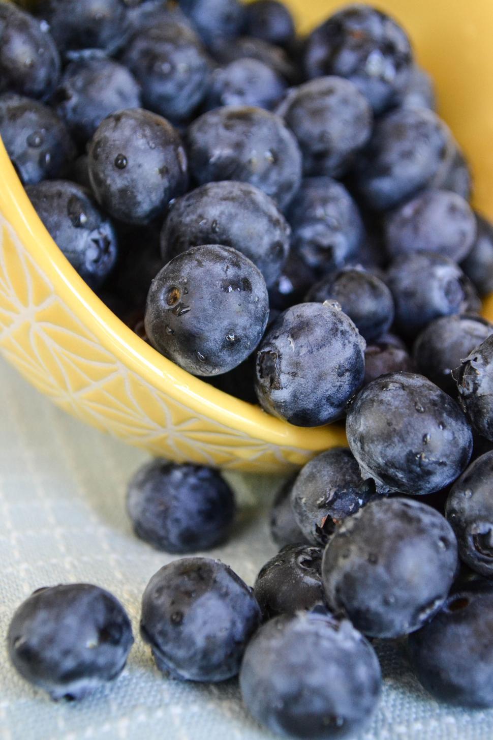 Free Image of Close-up of fresh blueberries spilling from yellow bowl 