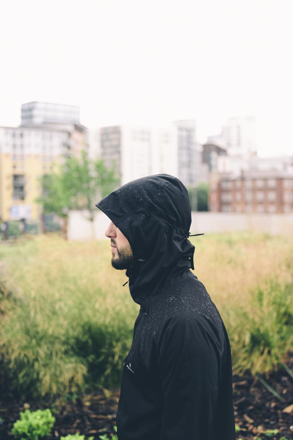 Free Image of Person in a black raincoat with city skyline background. 