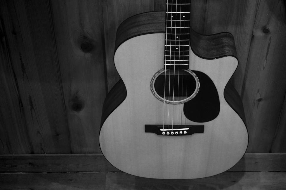 Free Image of Wooden acoustic guitar leaning against a rustic wall. 