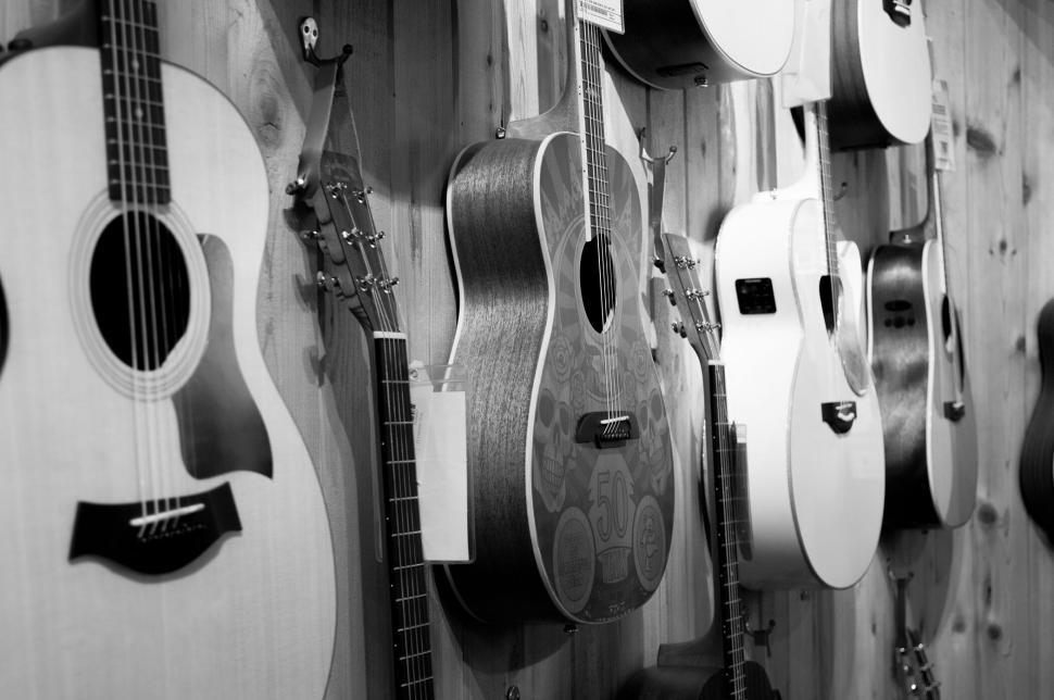 Free Image of Collection of guitars hanging on wooden wall display. 
