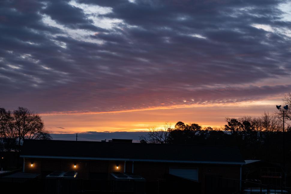 Free Image of Dramatic sunset over silhouetted buildings and trees 