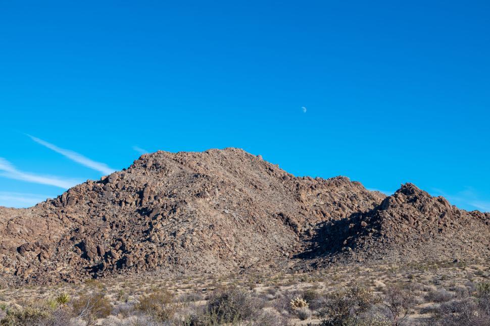 Free Image of Rocky mountain under bright blue sky with moon visible. 