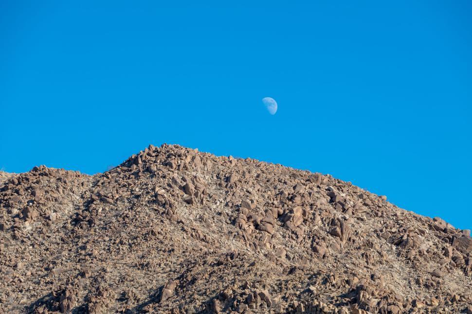 Free Image of Rocky hill with moon in clear blue daytime sky 