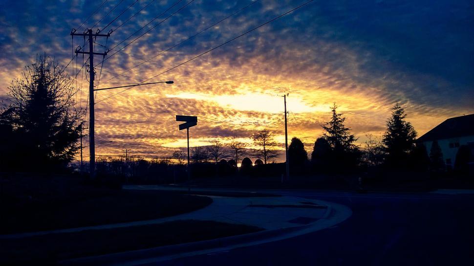 Free Image of Dramatic sunset over a suburban street with streetlights 