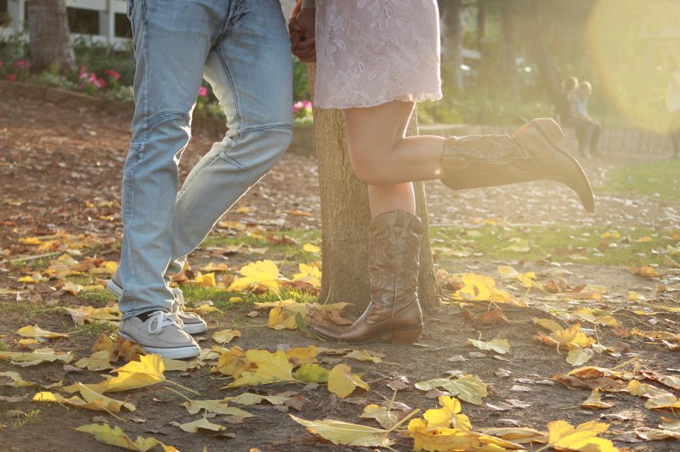 Free Image of Couple standing together in park covered with leaves 