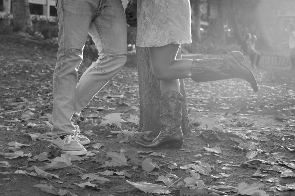 Free Image of Couple in park amidst fallen leaves, black and white 