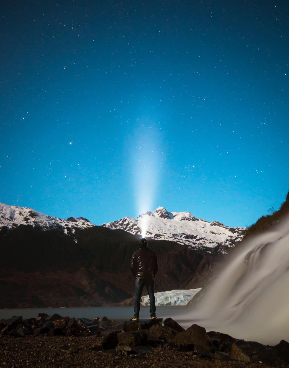 Free Image of Lone Figure Stands in Mountains with Headlamp Sky Stars 