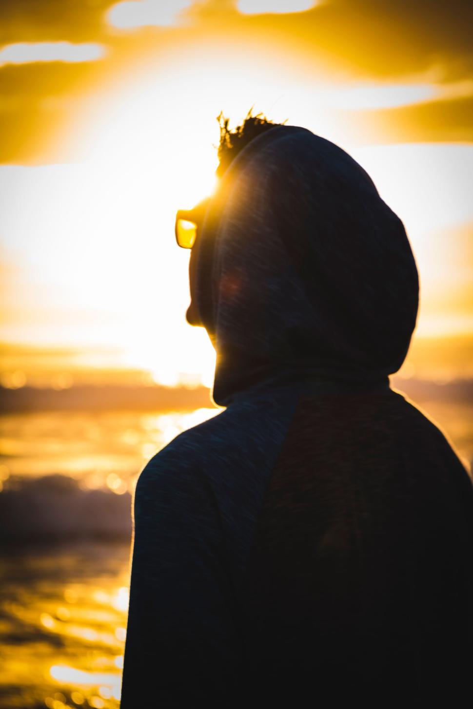 Free Image of Silhouette of Person Watching Sun Set Over Ocean Waves 