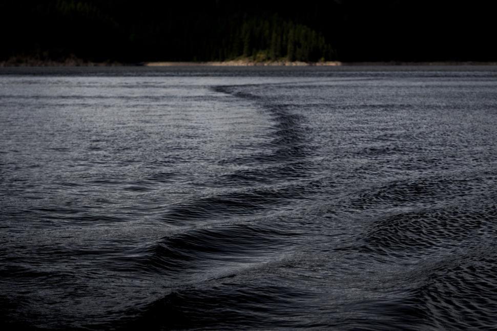 Free Image of Dark rippling water reflecting the sky above at dusk 
