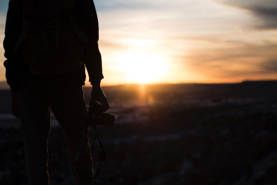 Free Image of Person holding camera at sunset with soft horizon glow 