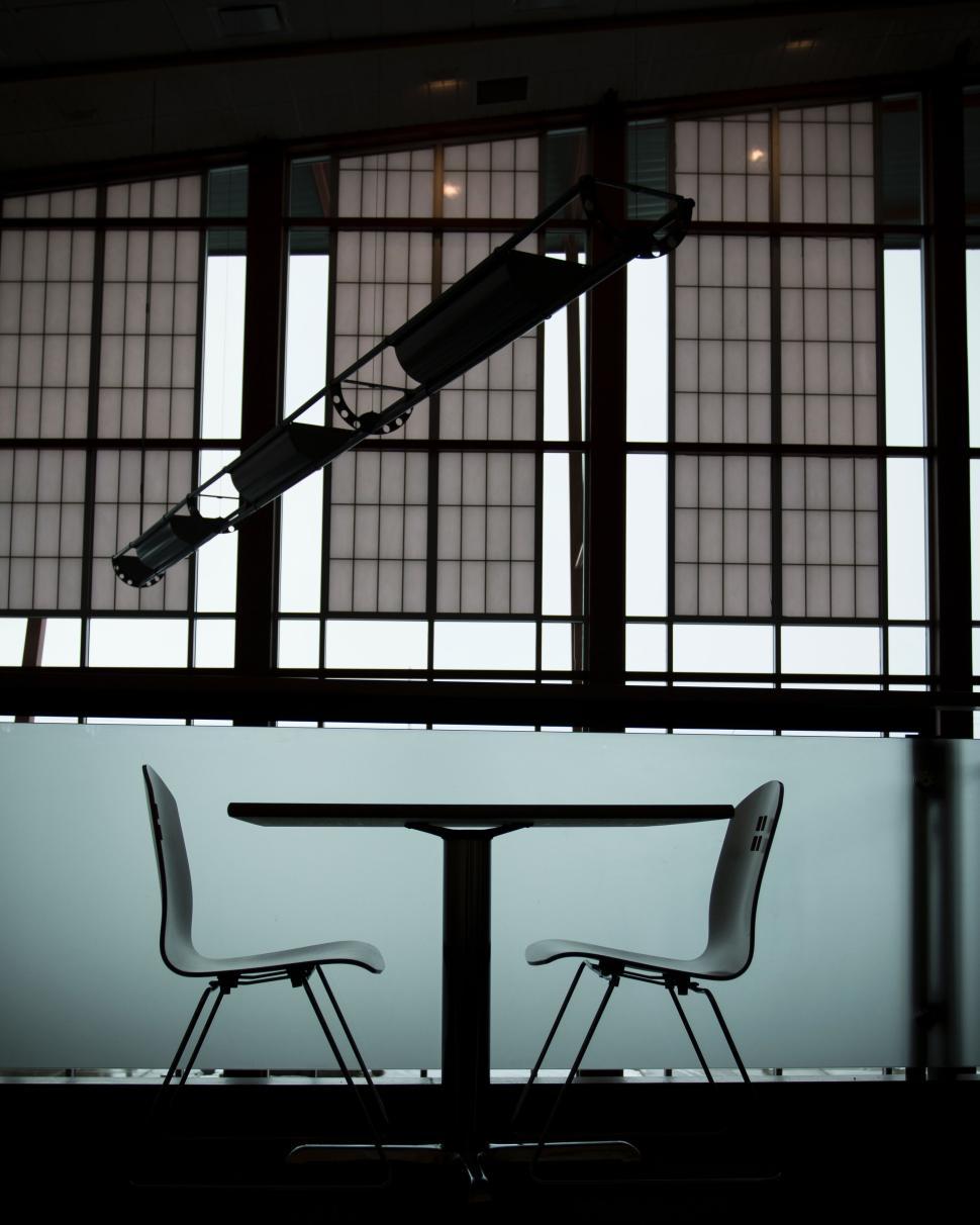 Free Image of Two modern white chairs at a sleek table by large windows. 