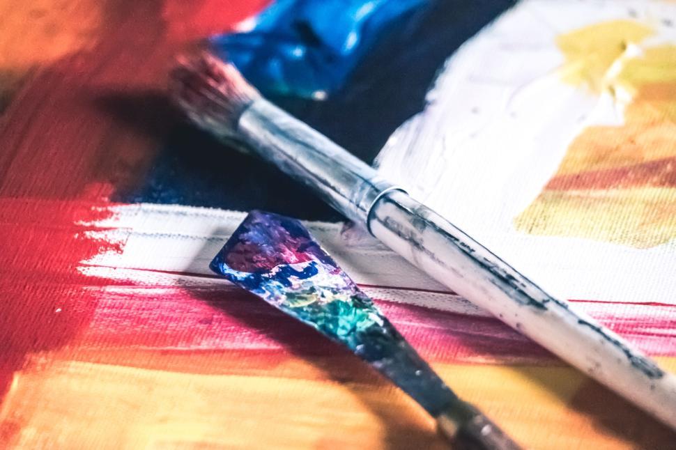 Free Image of Messy paintbrushes and tools on an artist s canvas 