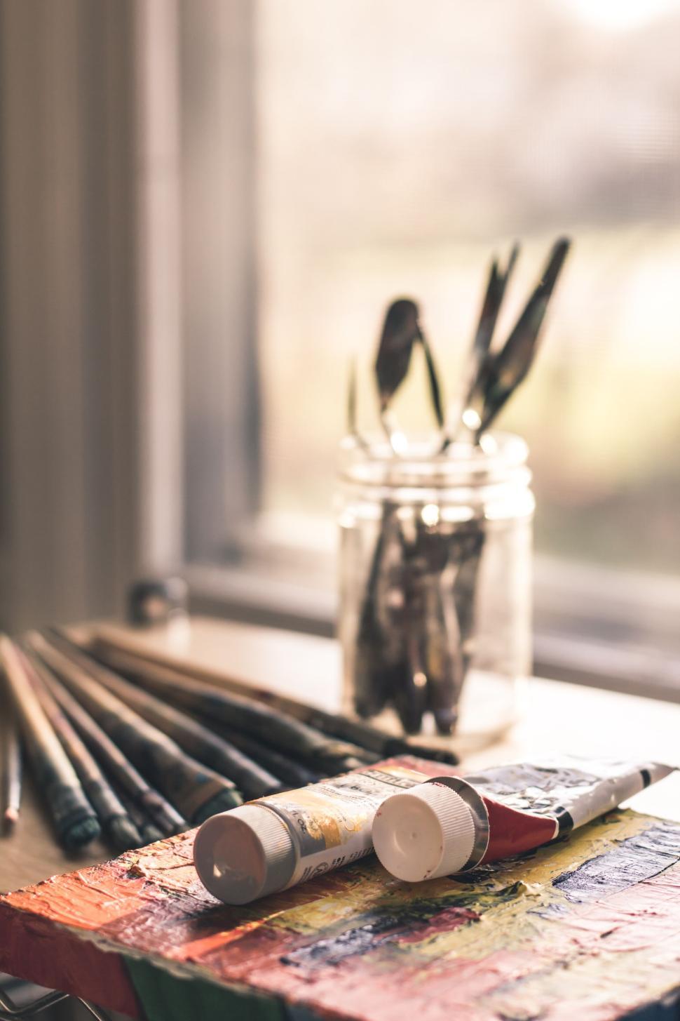 Free Image of Paintbrushes in jar with paints beside window in studio 