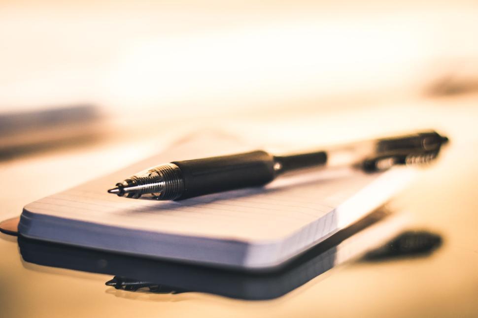 Free Image of Ballpoint pen resting on notebook with soft lighting. 
