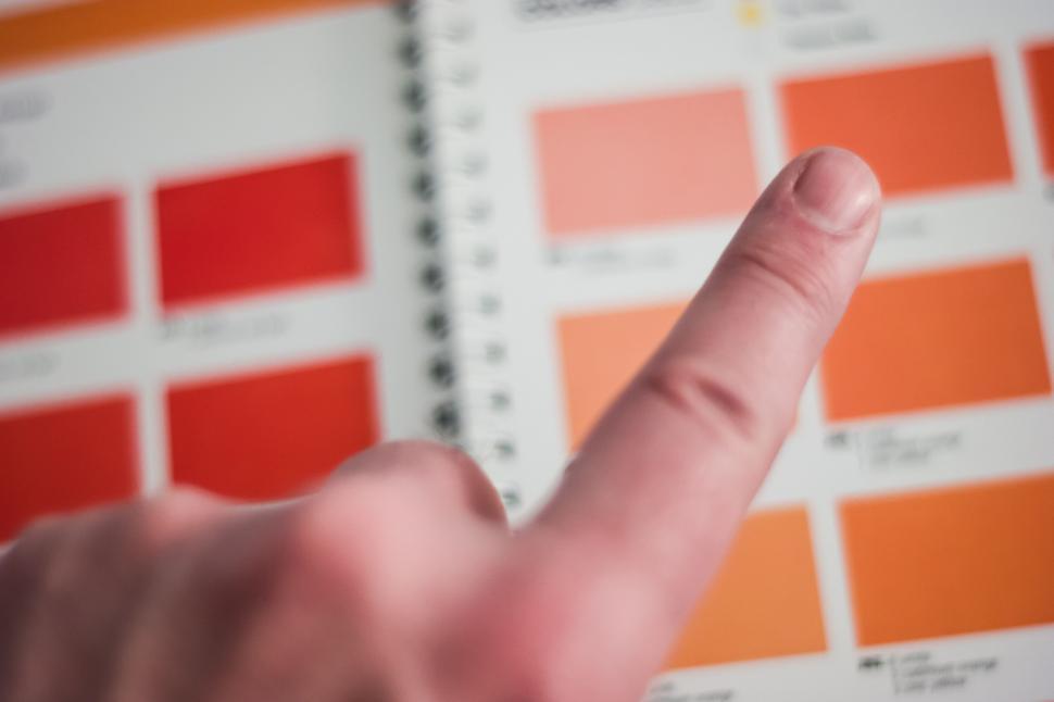Free Image of Finger points toward a vibrant color palette in catalog. 