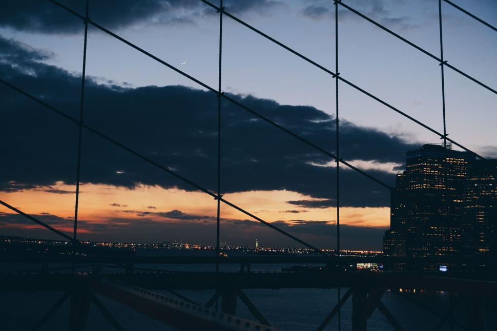 Free Image of Dusk over city skyline viewed through bridge cables 
