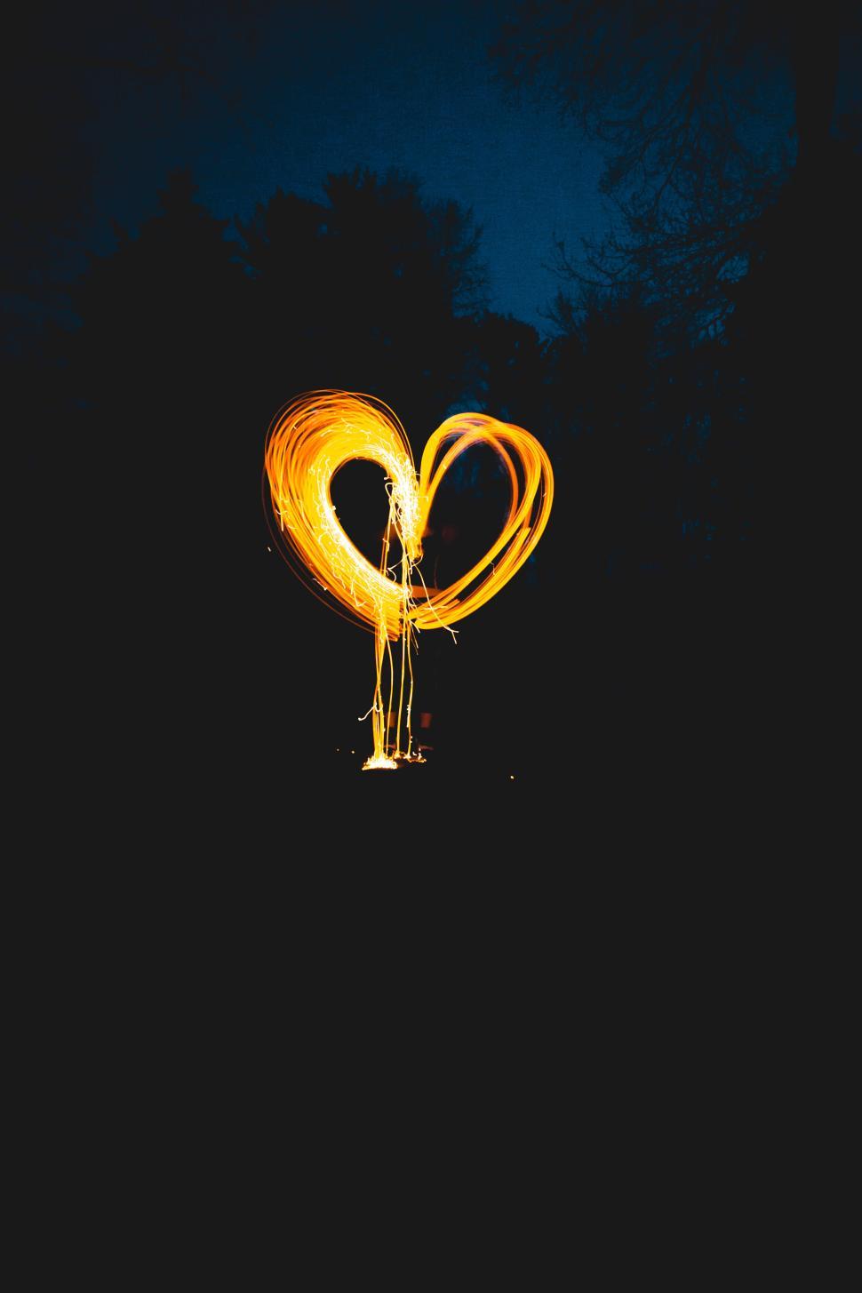 Free Image of Heart-shaped light trail amidst dark forest scenery 