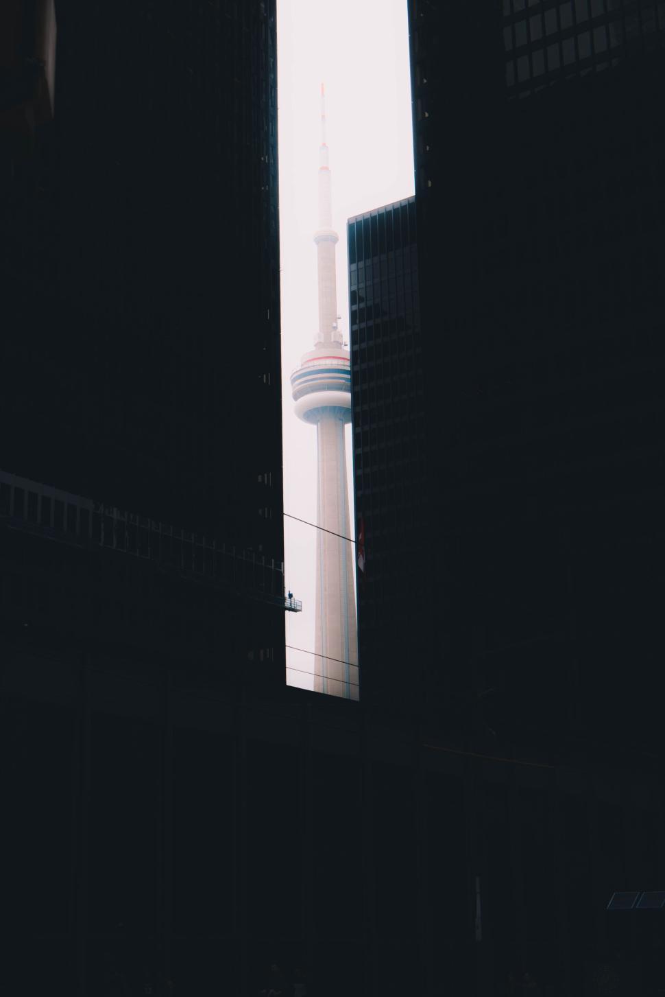 Free Image of Television tower seen between two dark buildings 