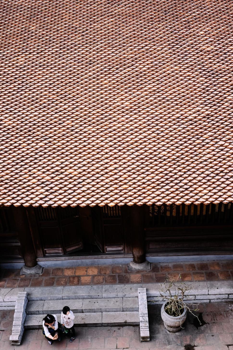 Free Image of Aerial view of two people conversing by a brick roof 