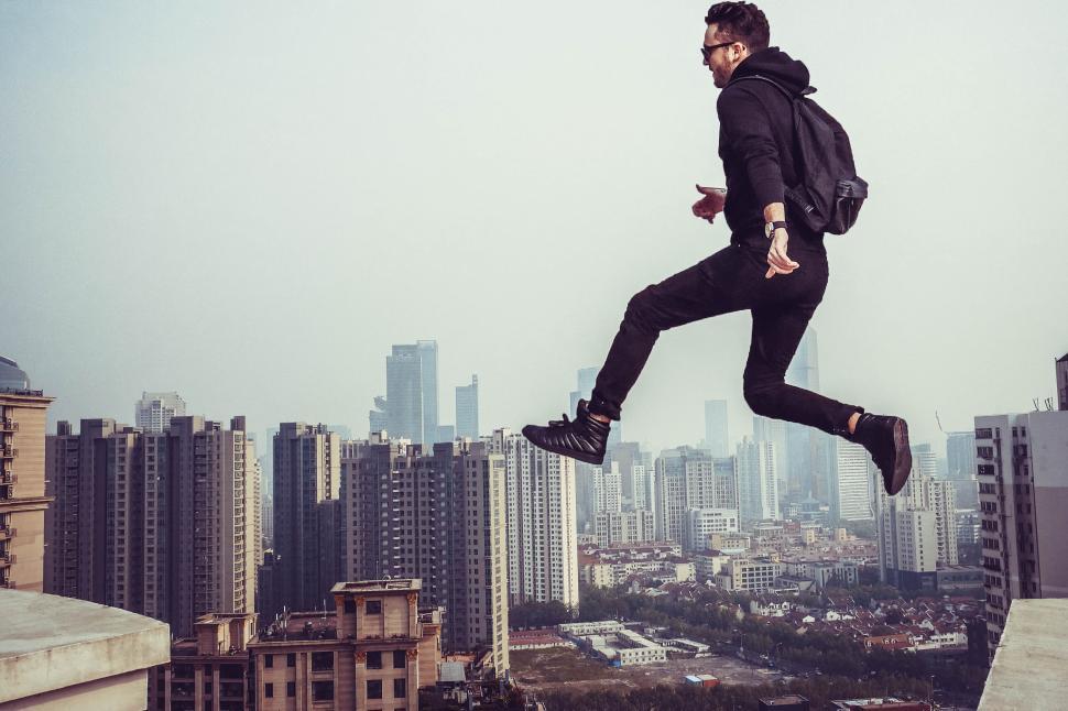 Free Image of Person jumping between buildings in urban cityscape 