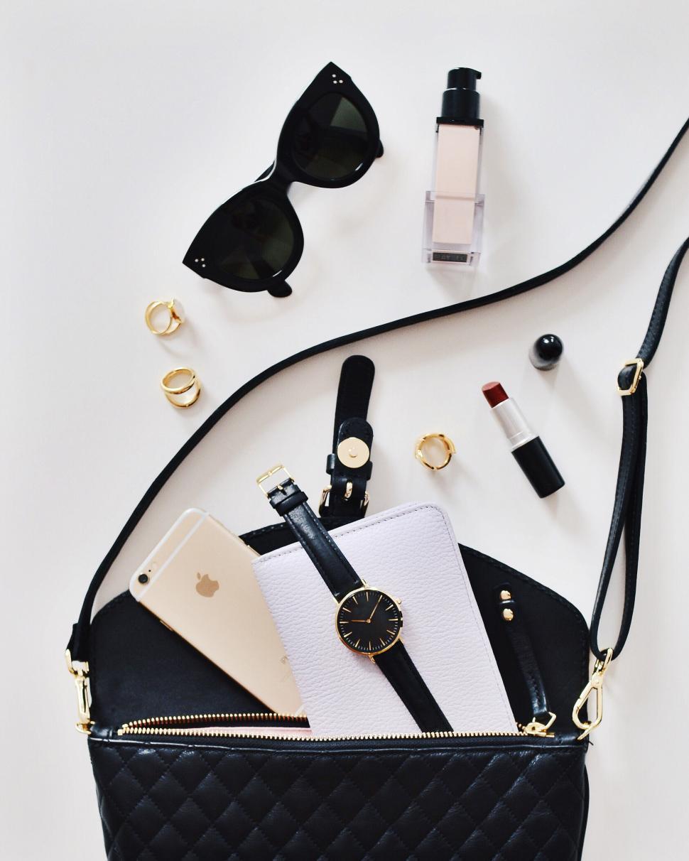Free Image of Black quilted bag with essentials, flatlay on white. 