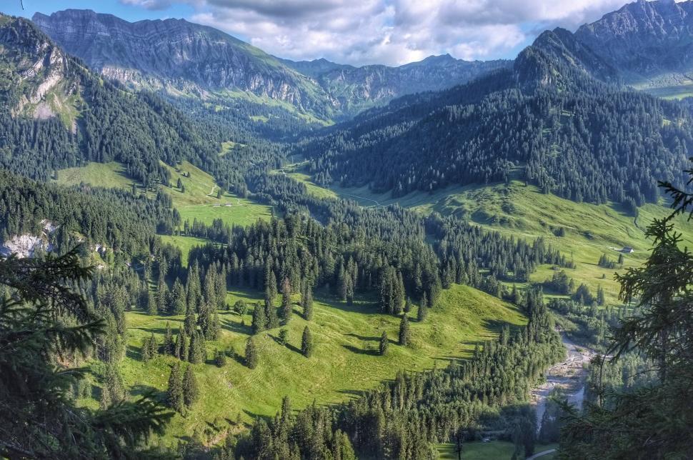 Free Image of Lush green valley surrounded by mountains under cloudy sky 