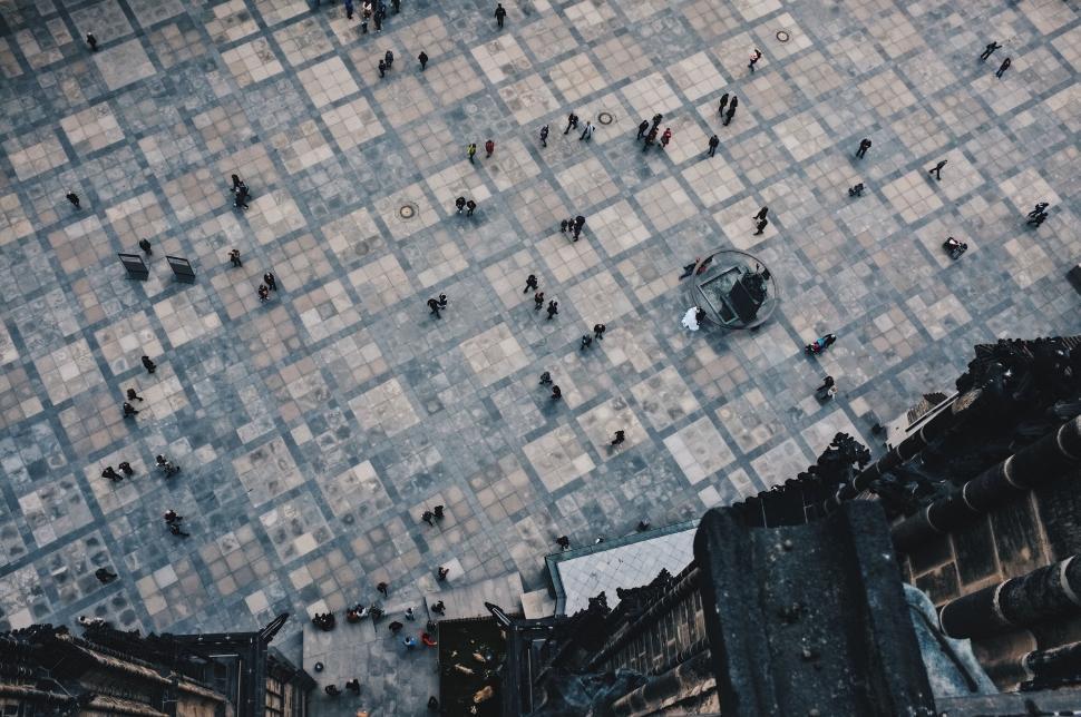 Free Image of People walking on large tiled square in urban area from above 