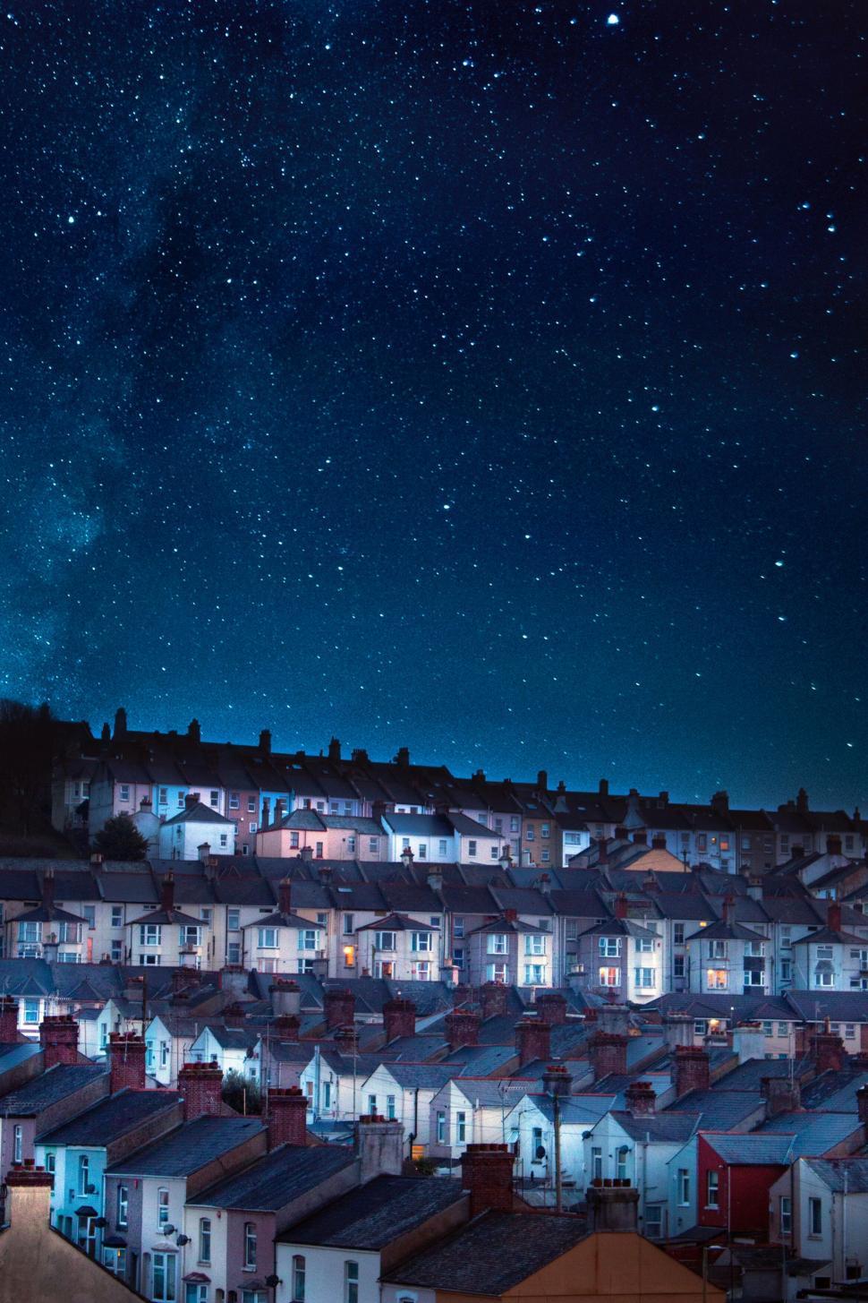 Free Image of Starry night sky over rows of houses on a hill 