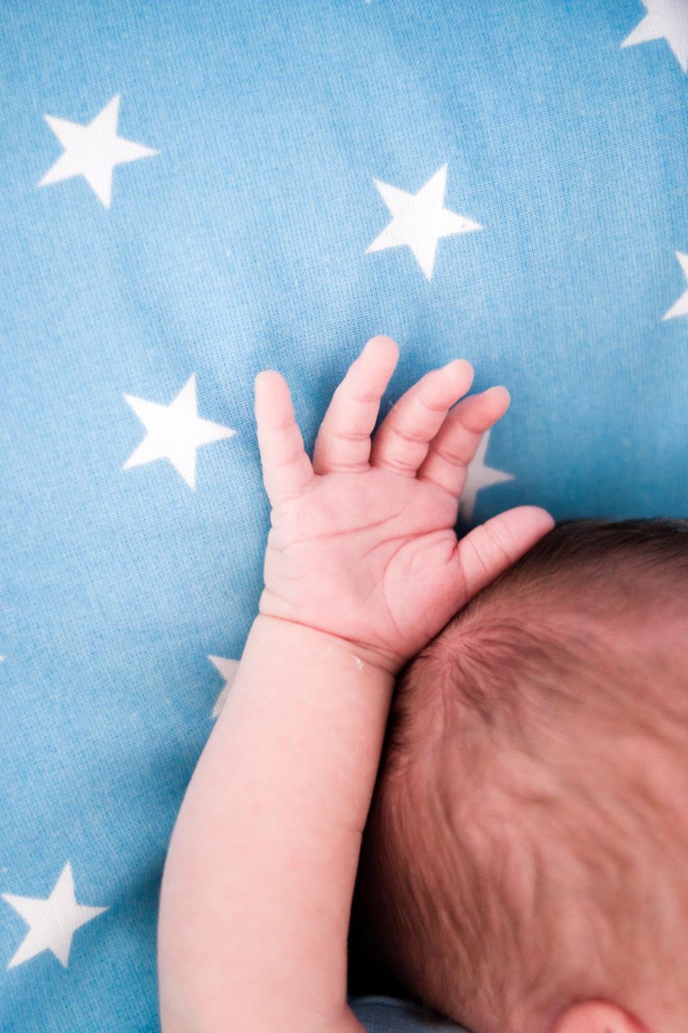 Free Image of Baby s hand stretched out on a star-patterned blanket. 