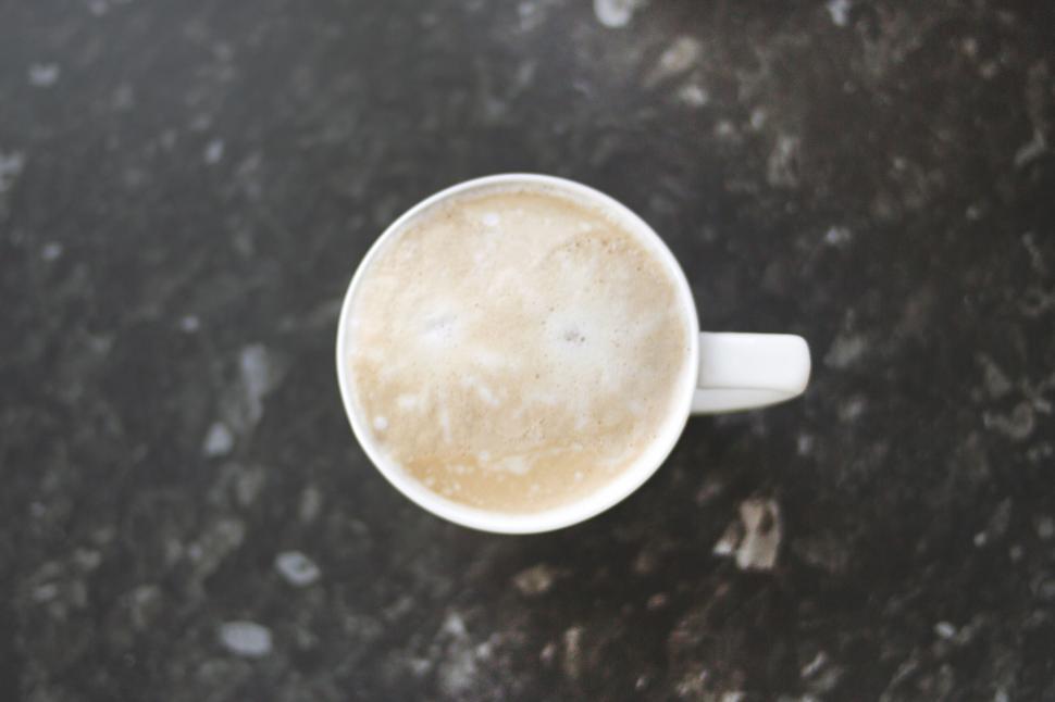 Free Image of Aerial view of a frothy coffee cup on a dark surface. 