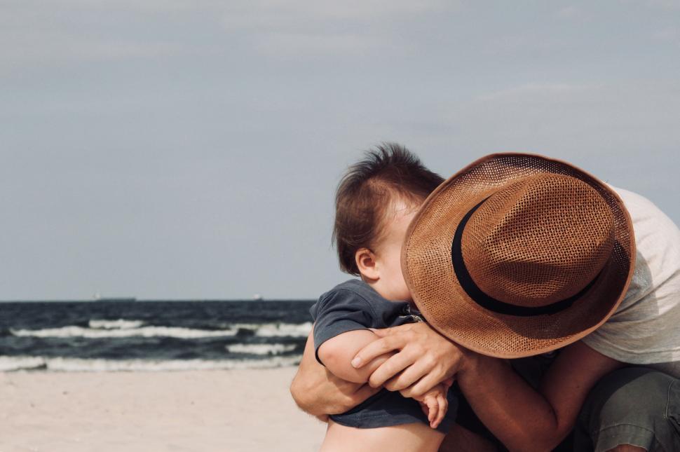 Free Image of Adult embracing a child on a sandy beach 