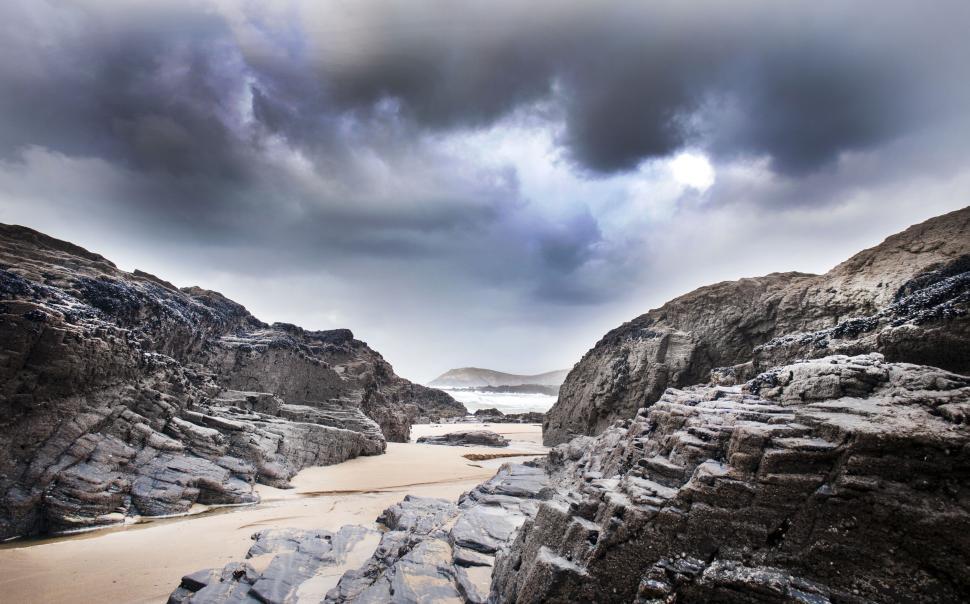 Free Image of Rocky landscape with cloudy sky and sandy path. 