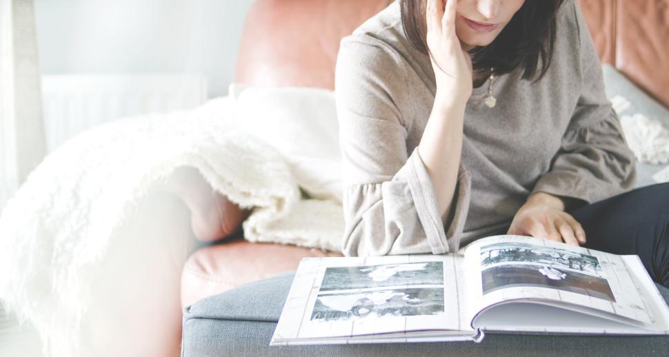 Free Image of Person sitting on couch flipping through photo album. 